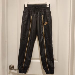Large sized kids black and gold lined Nike track pants